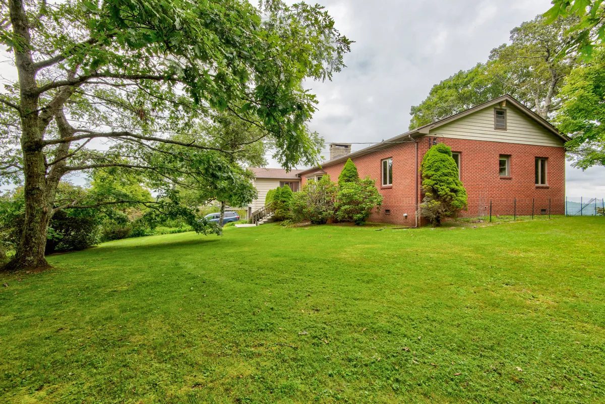 This image showcases a charming brick house surrounded by a lush green lawn and mature trees. The expansive yard provides ample open space for outdoor games, picnics, and pet-friendly strolls, all under the tranquil canopy of large trees. The setting is ideal for family gatherings and outdoor play, directly reflecting the section's emphasis on multi-generational experiences.
