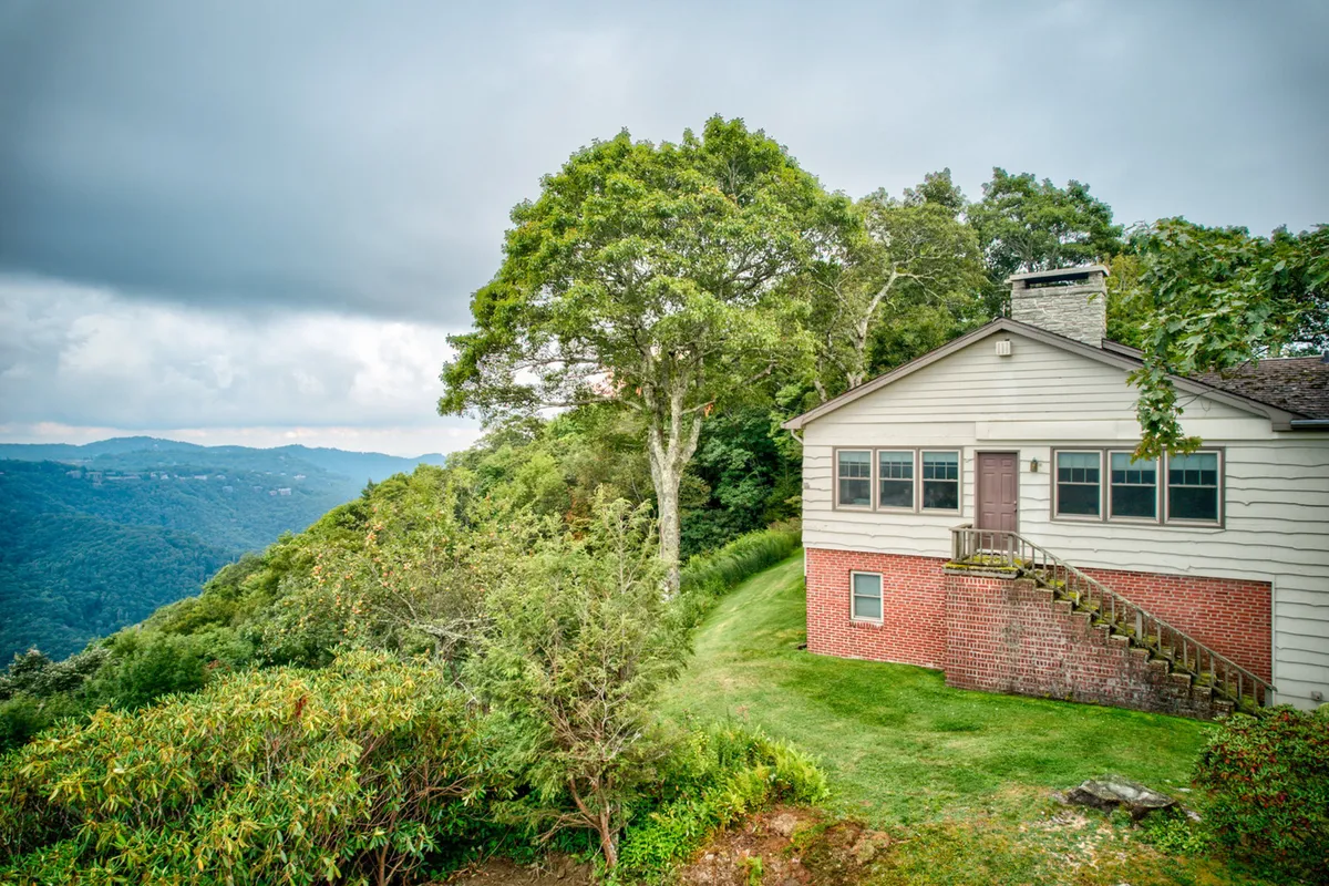 This image captures the house set against a backdrop of majestic mountains, with a prominent tree in the foreground. The tranquil scene suggests opportunities for hiking, picnicking, and observing nature—all directly referenced in the narrative about local adventures and scenic exploration.