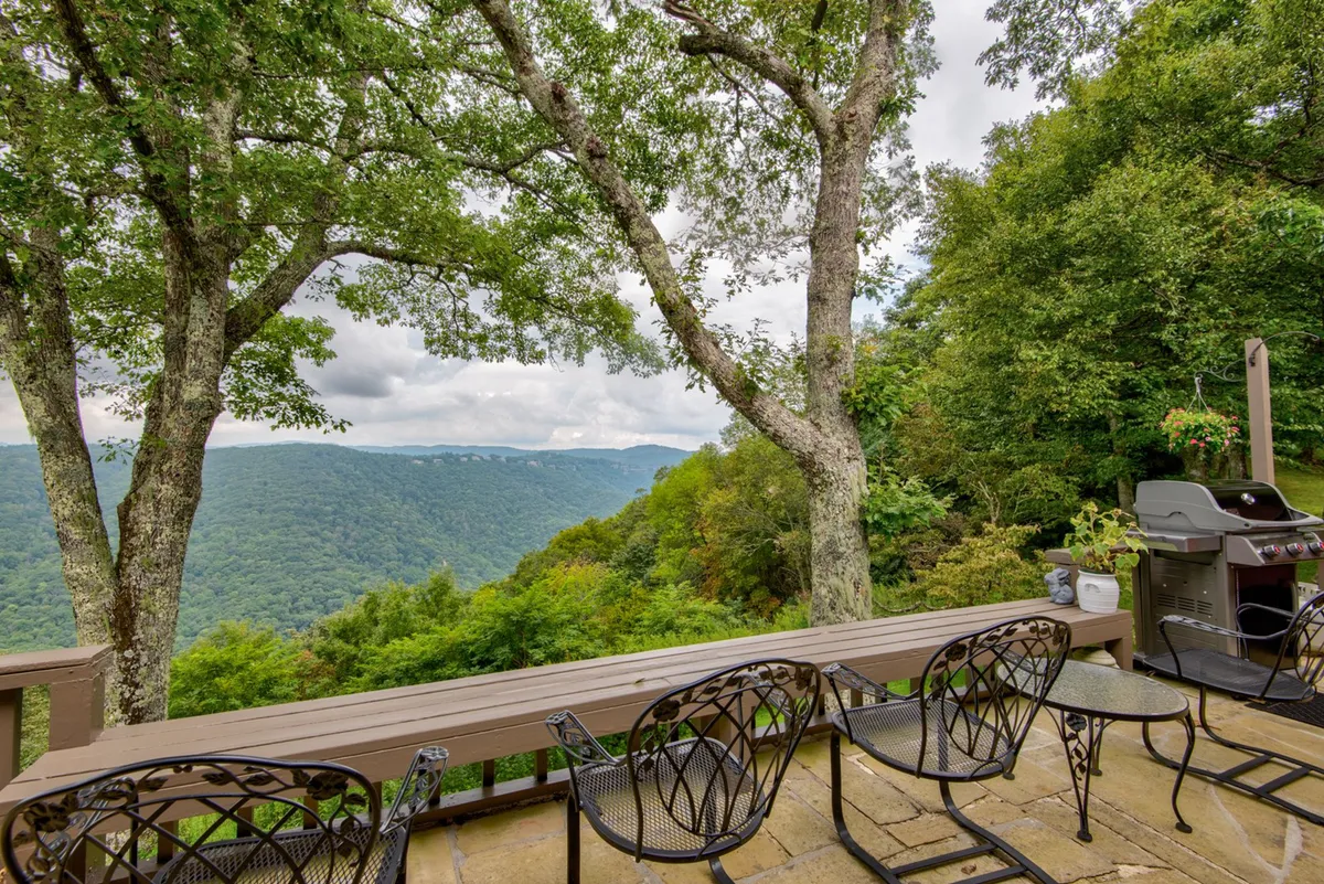 A serene outdoor deck with comfortable seating, a grill, and sweeping mountain vistas. The space is designed for al fresco dining, sunset toasts, and relaxed gatherings, with the mountains providing a stunning backdrop.