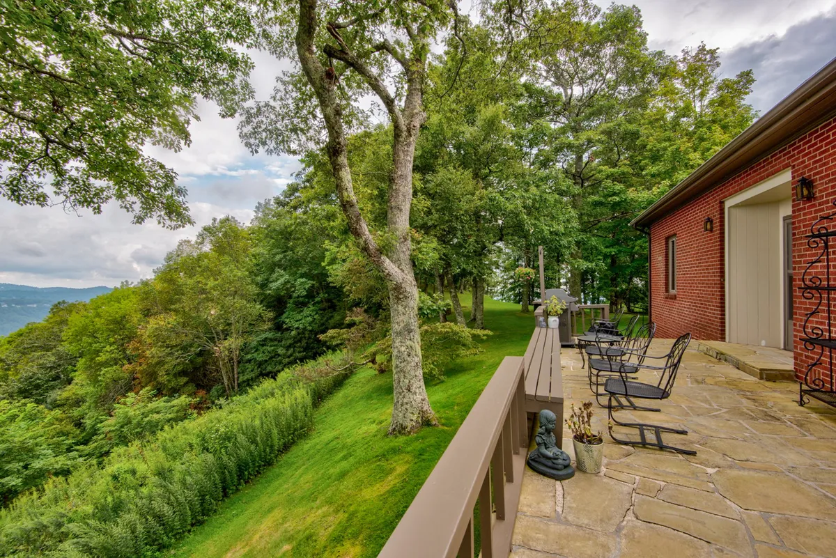 A serene patio seating area overlooking lush greenery and distant mountain views, enhanced by decorative touches and open skies. The scene suggests relaxation after outdoor activities, as well as an ideal vantage to observe sunrises or wildlife from the privacy of the property.